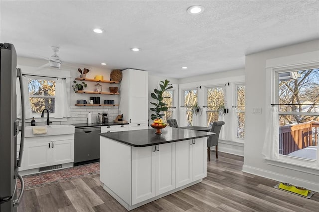 kitchen featuring dark countertops, backsplash, dark wood-type flooring, freestanding refrigerator, and dishwasher