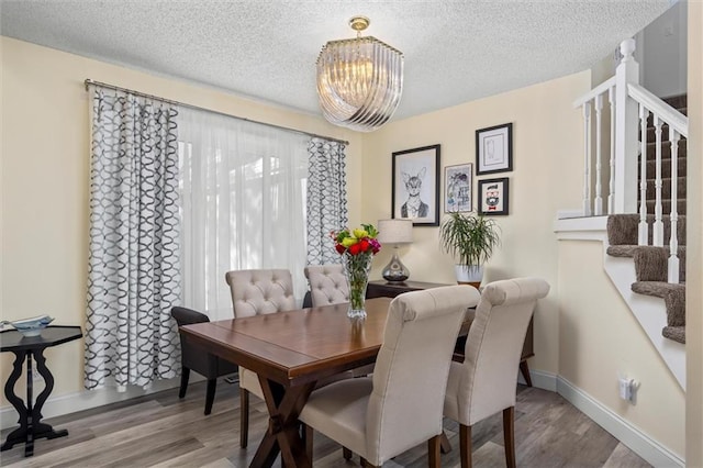 dining area with stairway, a notable chandelier, a textured ceiling, and wood finished floors