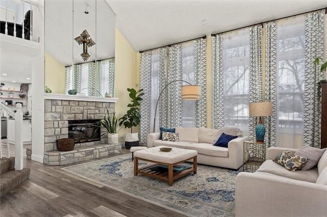 living area with a fireplace, stairway, a wealth of natural light, and wood finished floors