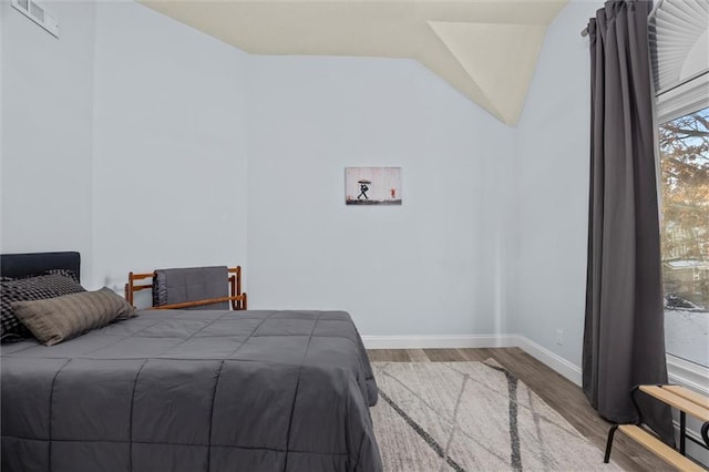 bedroom featuring lofted ceiling, wood finished floors, and baseboards