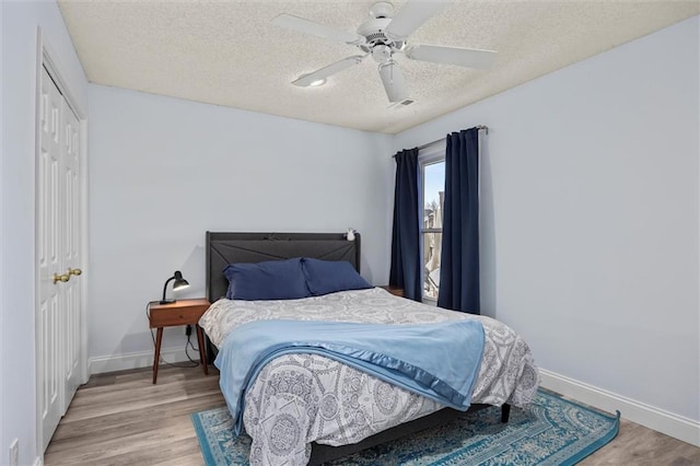 bedroom featuring visible vents, baseboards, wood finished floors, a textured ceiling, and a closet