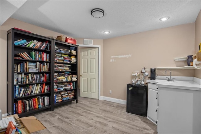 interior space featuring light wood-style floors, baseboards, visible vents, and a sink