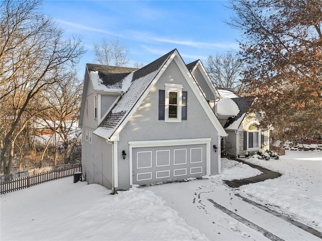 view of snowy exterior with a shingled roof, fence, and stucco siding