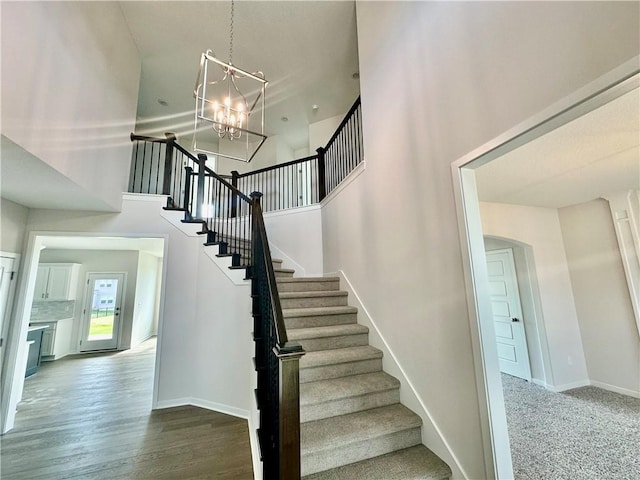 stairs with a chandelier, a high ceiling, and hardwood / wood-style flooring