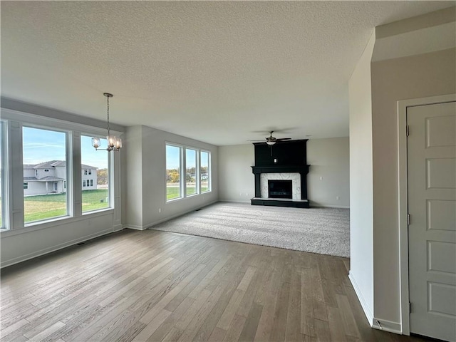 unfurnished living room featuring hardwood / wood-style floors, a textured ceiling, a fireplace, and an inviting chandelier