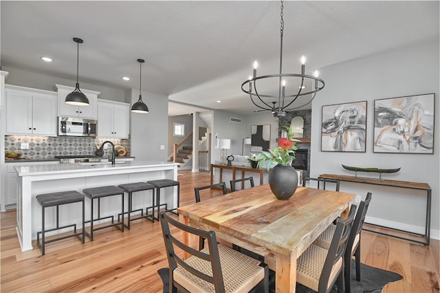 dining room with light hardwood / wood-style floors, an inviting chandelier, and sink