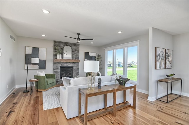 living room with ceiling fan, a fireplace, and light wood-type flooring