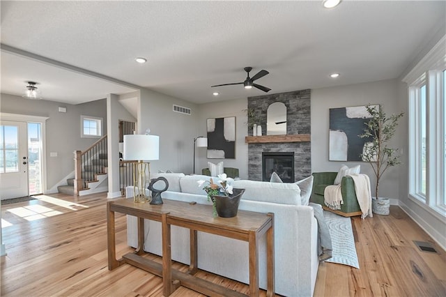 living room with a fireplace, light hardwood / wood-style floors, and ceiling fan