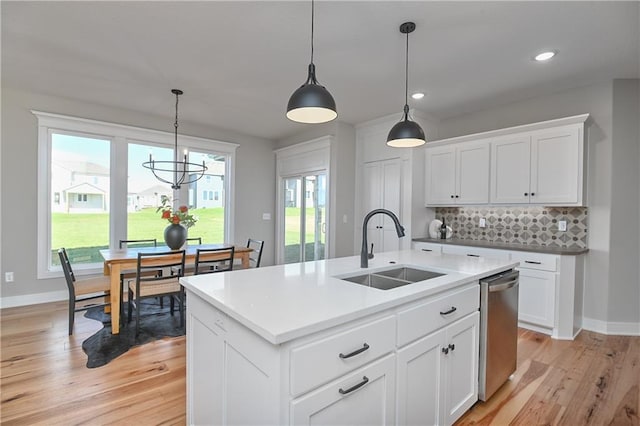 kitchen with tasteful backsplash, stainless steel dishwasher, a kitchen island with sink, sink, and pendant lighting