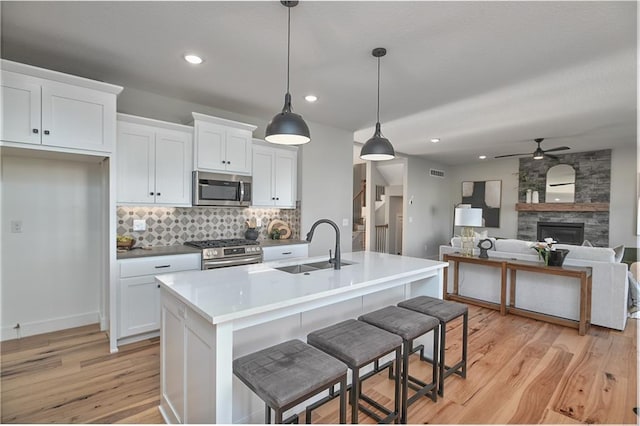 kitchen featuring a kitchen island with sink, white cabinetry, sink, and stainless steel appliances