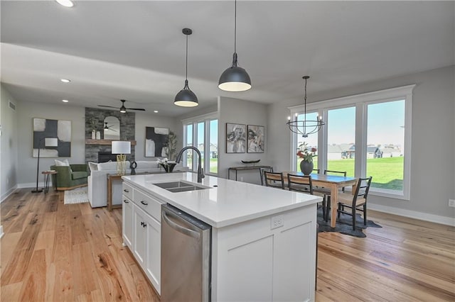 kitchen with pendant lighting, a kitchen island with sink, white cabinets, sink, and stainless steel dishwasher