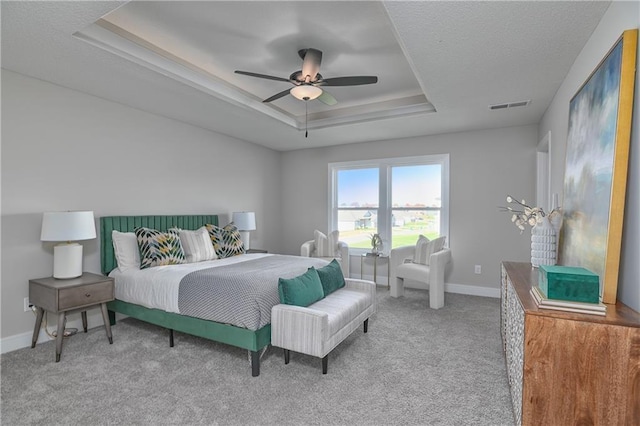 carpeted bedroom with a raised ceiling and ceiling fan