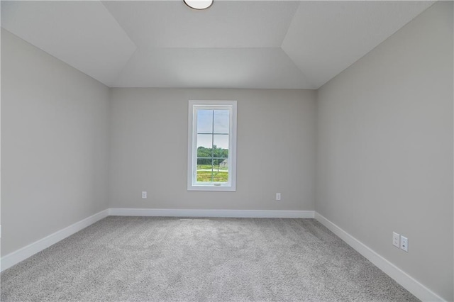 carpeted spare room featuring vaulted ceiling