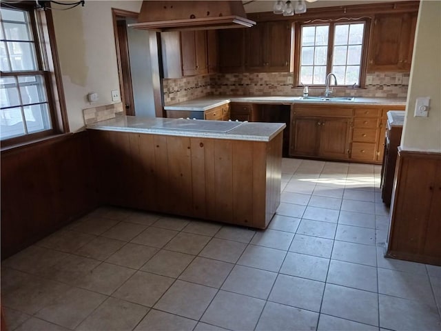 kitchen with sink, cooktop, backsplash, kitchen peninsula, and light tile patterned floors