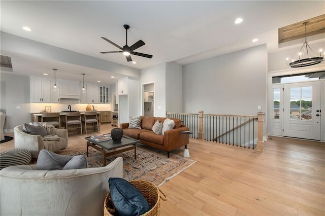 living room featuring ceiling fan with notable chandelier and light hardwood / wood-style floors