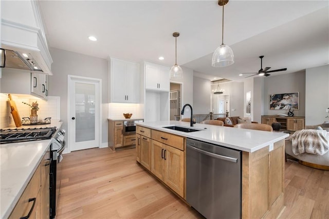 kitchen featuring sink, stainless steel appliances, tasteful backsplash, an island with sink, and white cabinets