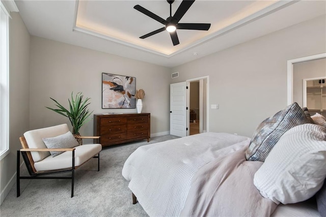 carpeted bedroom featuring a raised ceiling and ceiling fan