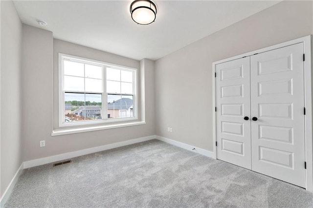 unfurnished bedroom with light carpet and a closet