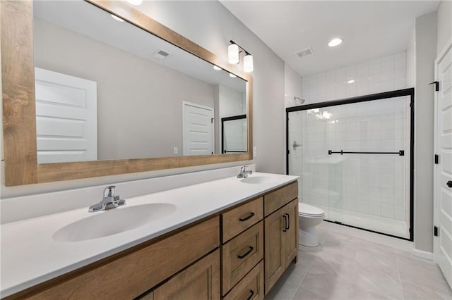 bathroom with toilet, vanity, tile patterned floors, and a shower with shower door