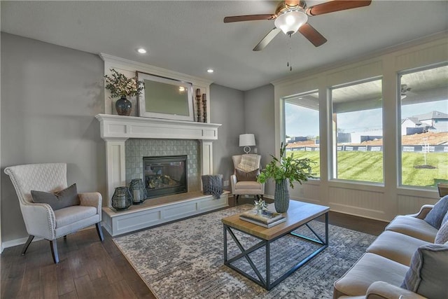 living room featuring ceiling fan, dark wood-type flooring, and a tile fireplace