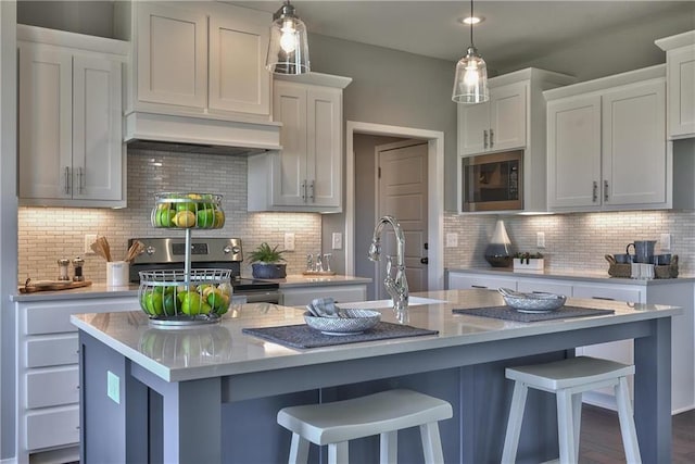 kitchen featuring white cabinets, built in microwave, and an island with sink