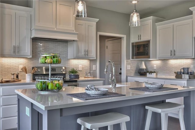 kitchen with backsplash, stainless steel electric stove, and an island with sink