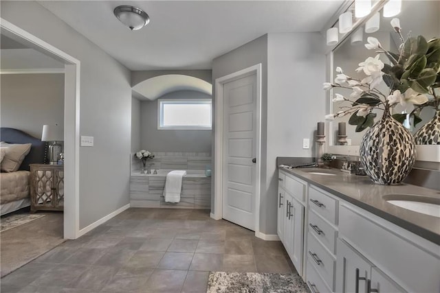 bathroom featuring tile patterned flooring, vanity, and tiled tub