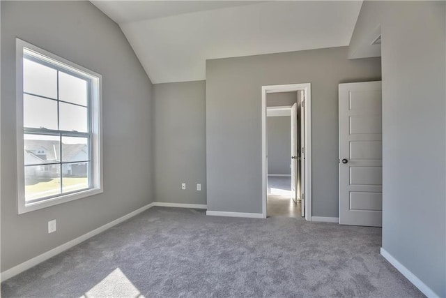 unfurnished bedroom featuring multiple windows, light colored carpet, and lofted ceiling