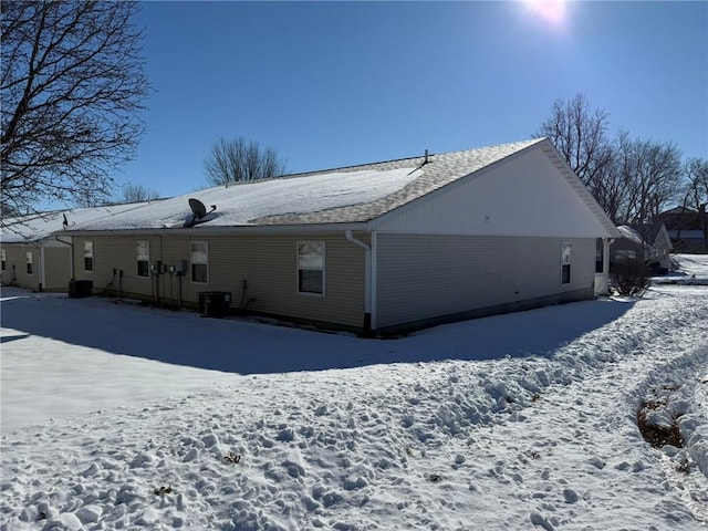 snow covered rear of property featuring cooling unit