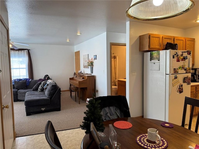 dining area with ceiling fan, light carpet, and a textured ceiling