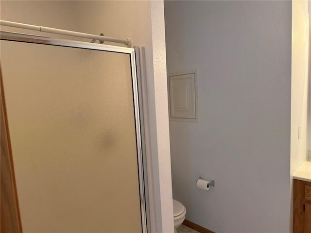 bathroom featuring toilet, a shower with door, and vanity