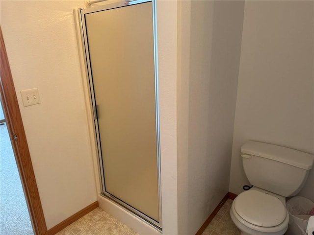 bathroom featuring a shower with door and toilet