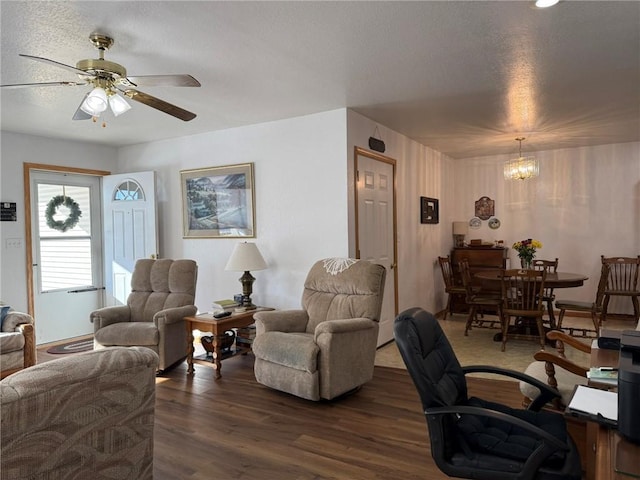 living room featuring ceiling fan with notable chandelier, a textured ceiling, and dark hardwood / wood-style flooring