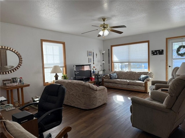 living room featuring a textured ceiling, ceiling fan, and dark wood-type flooring