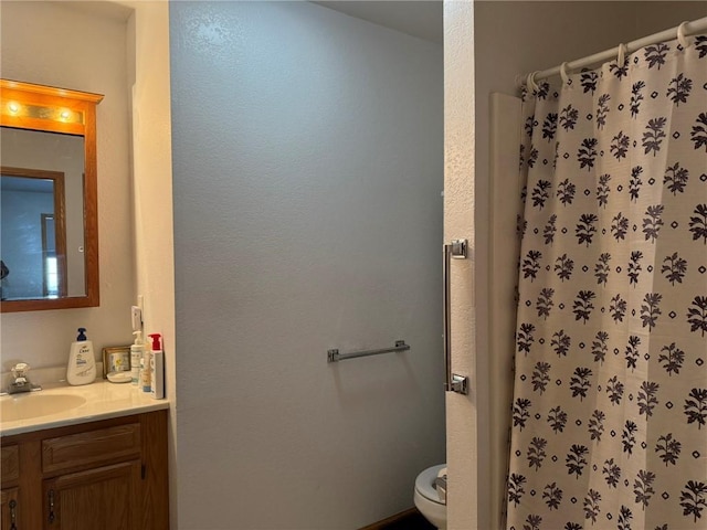 bathroom featuring toilet, a shower, and vanity