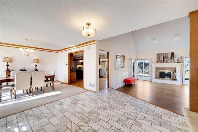 dining area featuring baseboards, visible vents, a glass covered fireplace, a textured ceiling, and a chandelier