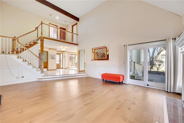 unfurnished living room with beam ceiling, a healthy amount of sunlight, a decorative wall, and wood finished floors