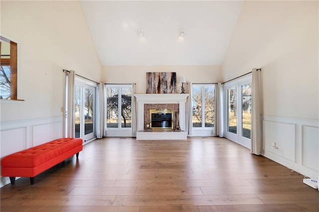 living area featuring a high end fireplace, plenty of natural light, and wood finished floors