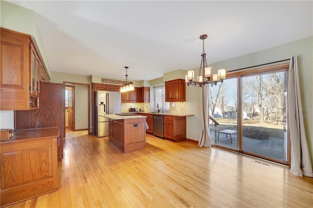 kitchen with visible vents, a center island, stainless steel appliances, light wood-style floors, and a chandelier