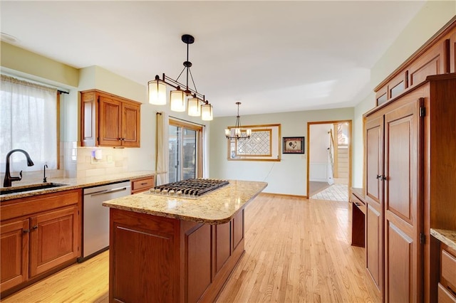 kitchen featuring light wood finished floors, a kitchen island, stainless steel appliances, and a sink