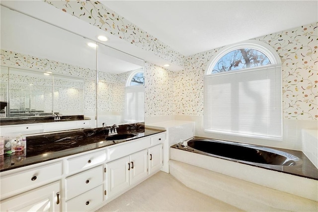 full bath featuring wallpapered walls, plenty of natural light, a bath, and vanity