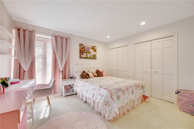 bedroom featuring multiple closets, recessed lighting, and light colored carpet