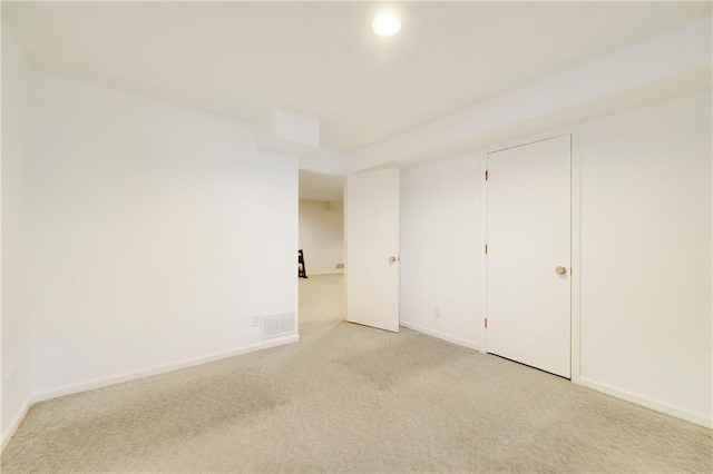 unfurnished room with baseboards, visible vents, and light colored carpet