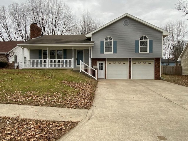 split level home featuring a front yard, covered porch, and a garage