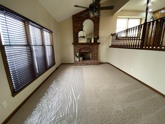 unfurnished living room with ceiling fan, vaulted ceiling, a fireplace, and plenty of natural light