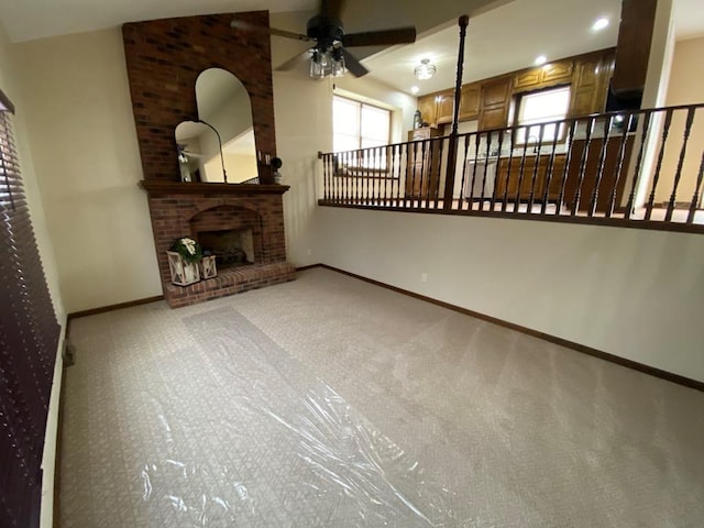 unfurnished living room with vaulted ceiling, ceiling fan, a fireplace, and light colored carpet