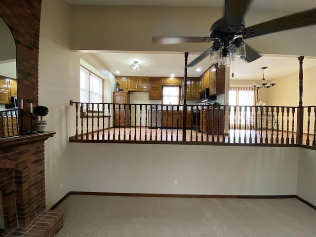 interior space with ceiling fan with notable chandelier, a wealth of natural light, and a fireplace