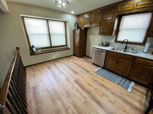 kitchen featuring light hardwood / wood-style floors, sink, stainless steel dishwasher, and tasteful backsplash