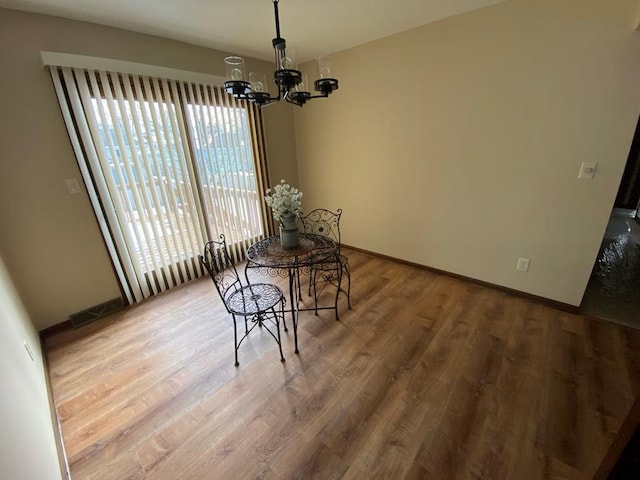 dining area with hardwood / wood-style flooring and an inviting chandelier