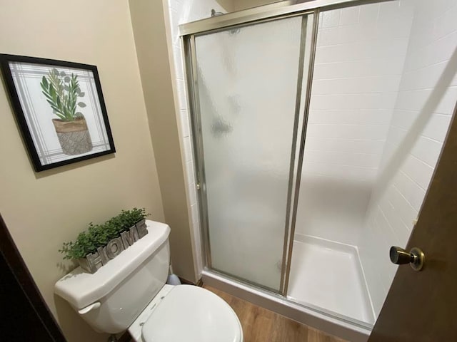 bathroom with an enclosed shower, toilet, and hardwood / wood-style floors